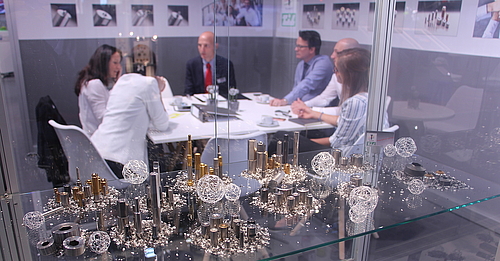 View through exhibition showcase with cold forming tools on Teudeloff team during a meeting